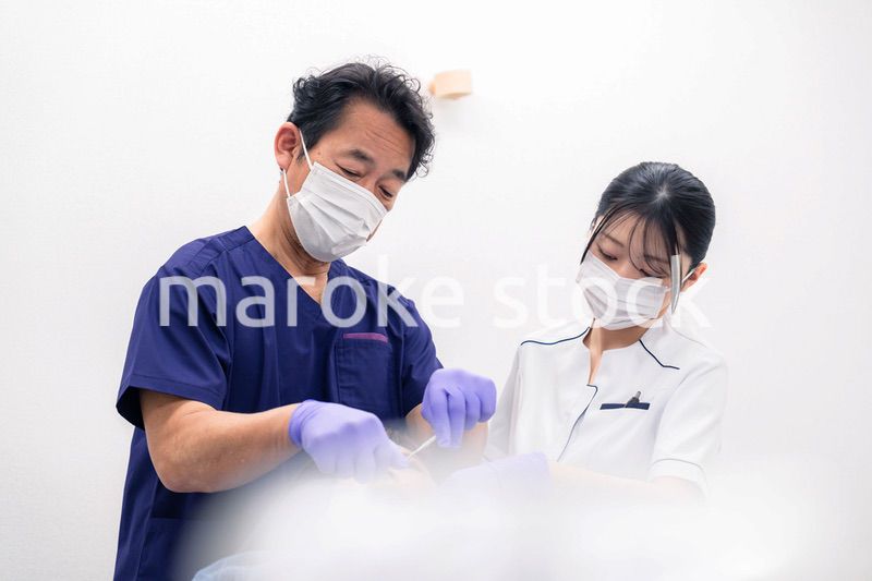 歯科治療をする歯科医師と歯科助手