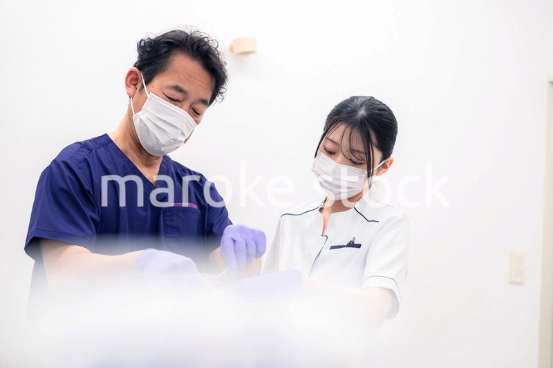 歯科治療をする歯科医師と歯科助手