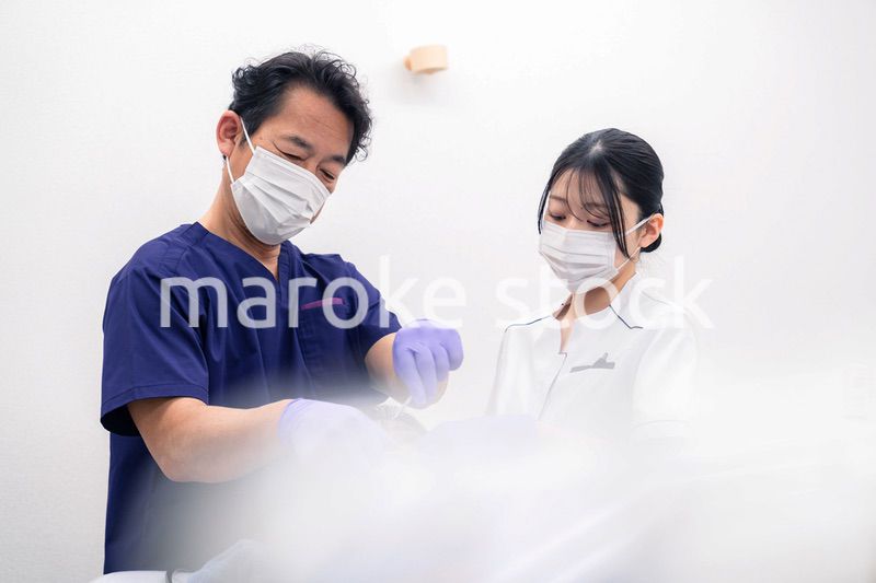 歯科治療をする歯科医師と歯科助手