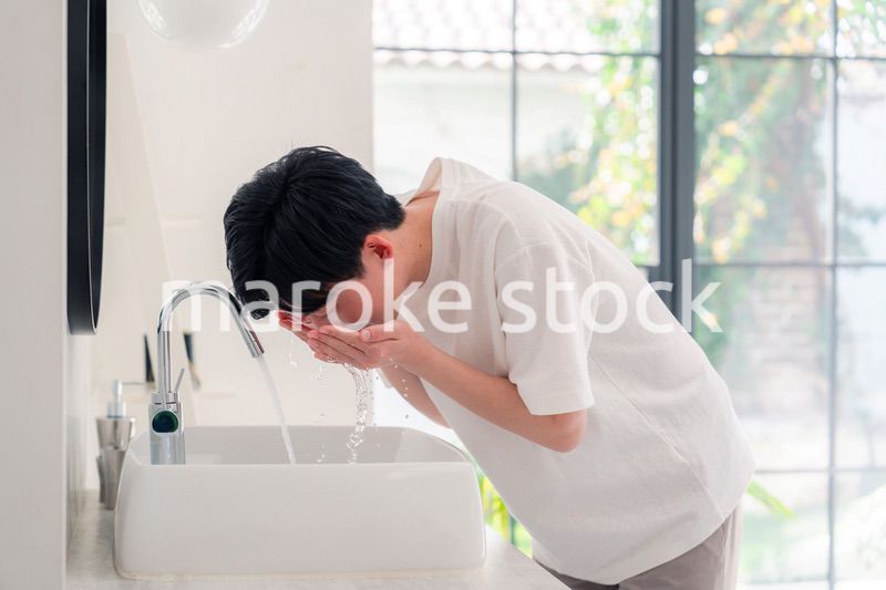 洗面所で洗顔をする若い男性