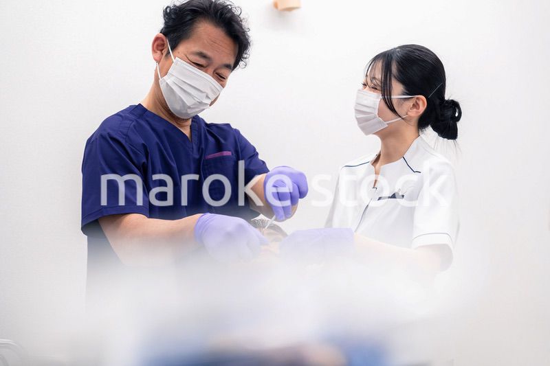 歯科治療をする歯科医師と歯科助手