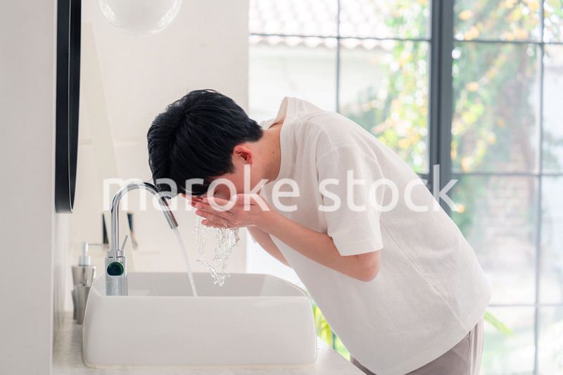 洗面所で洗顔をする若い男性