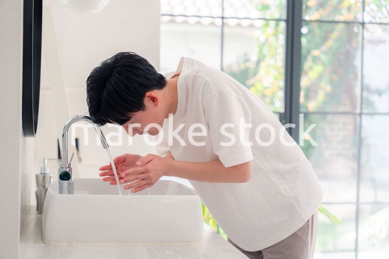 洗面所で洗顔をする若い男性
