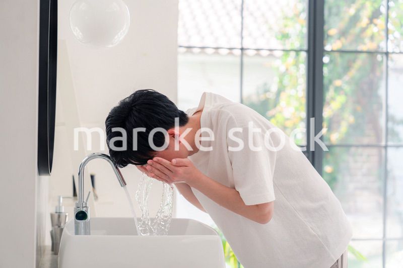 洗面所で洗顔をする若い男性
