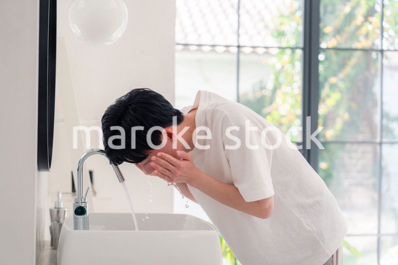 洗面所で洗顔をする若い男性