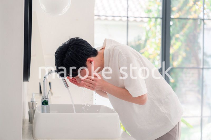 洗面所で洗顔をする若い男性