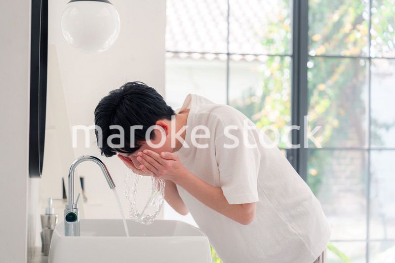 洗面所で洗顔をする若い男性