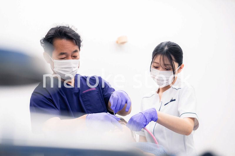 歯科治療をする歯科医師と歯科助手
