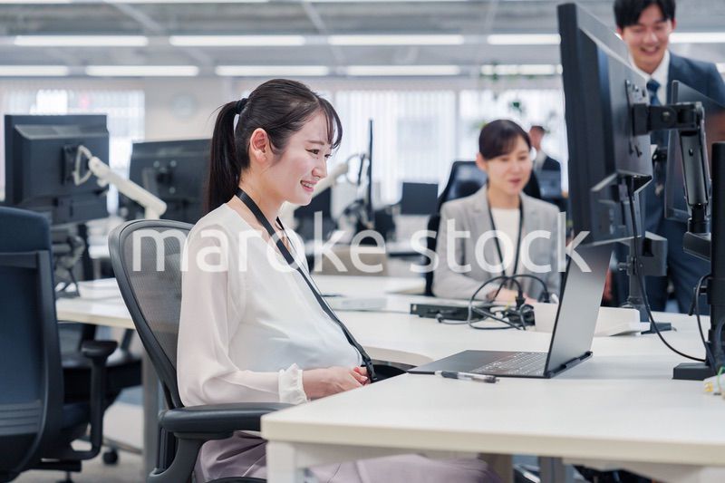 オフィスでデスクワークをする妊婦の女性