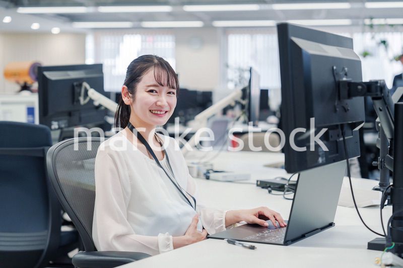 オフィスでデスクワークをする妊婦の女性