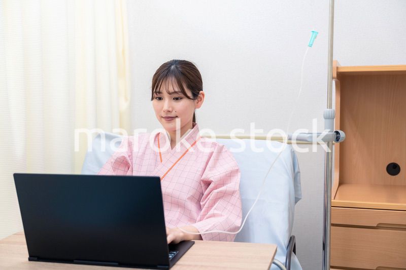 病室でパソコンを使う入院患者