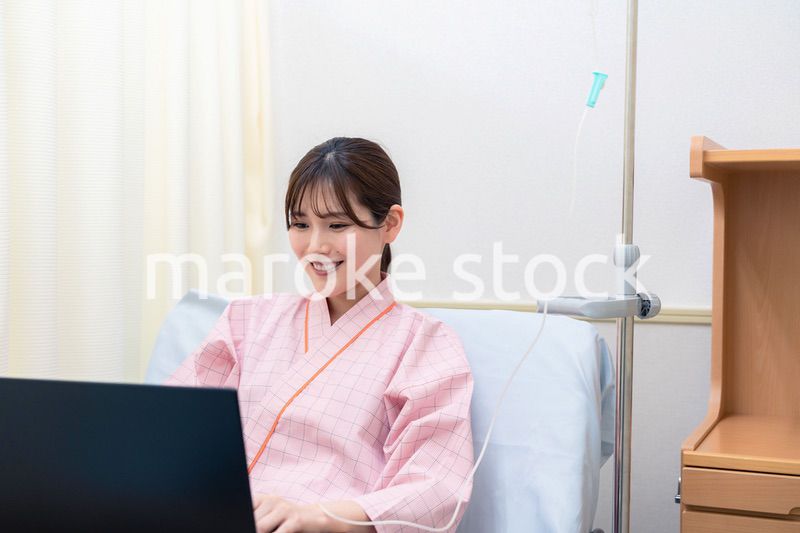 病室でパソコンを使う入院患者
