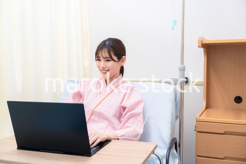 病室でパソコンを使う入院患者