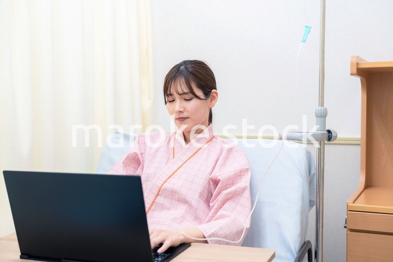病室でパソコンを使う入院患者