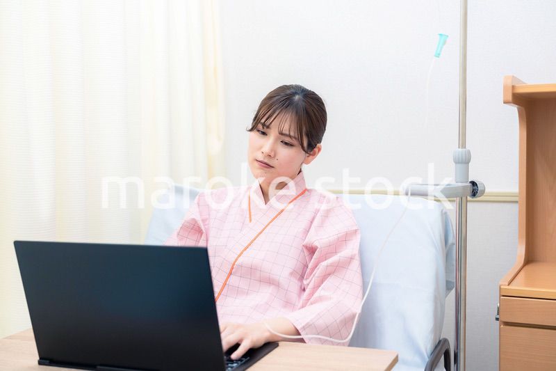 病室でパソコンを使う入院患者