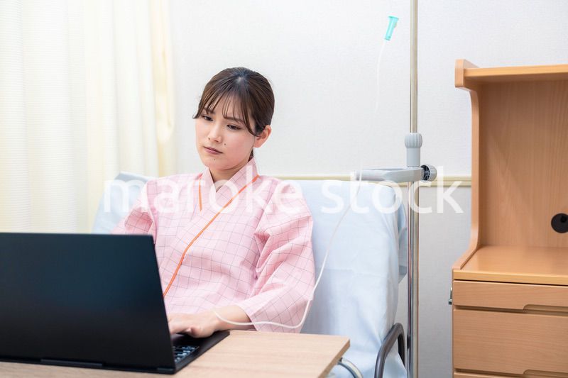 病室でパソコンを使う入院患者