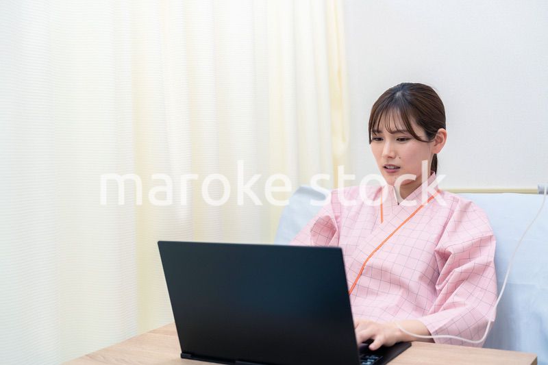 病室でパソコンを使う入院患者