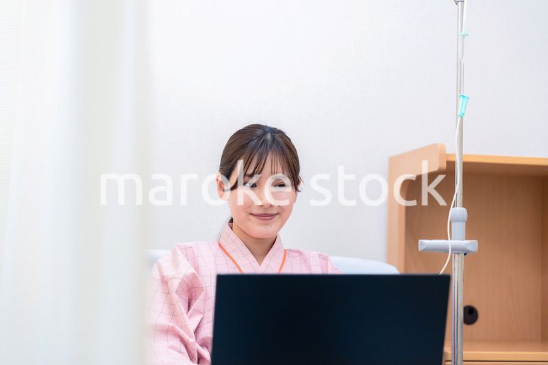 病室でパソコンを使う入院患者