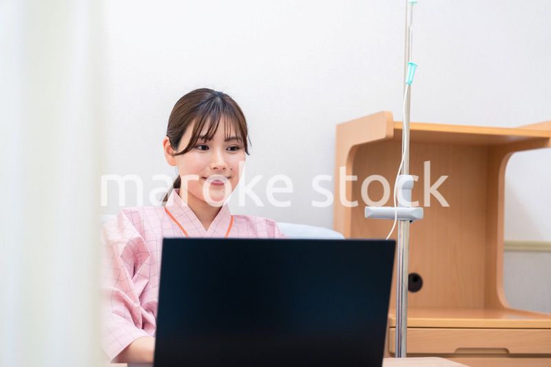 病室でパソコンを使う入院患者