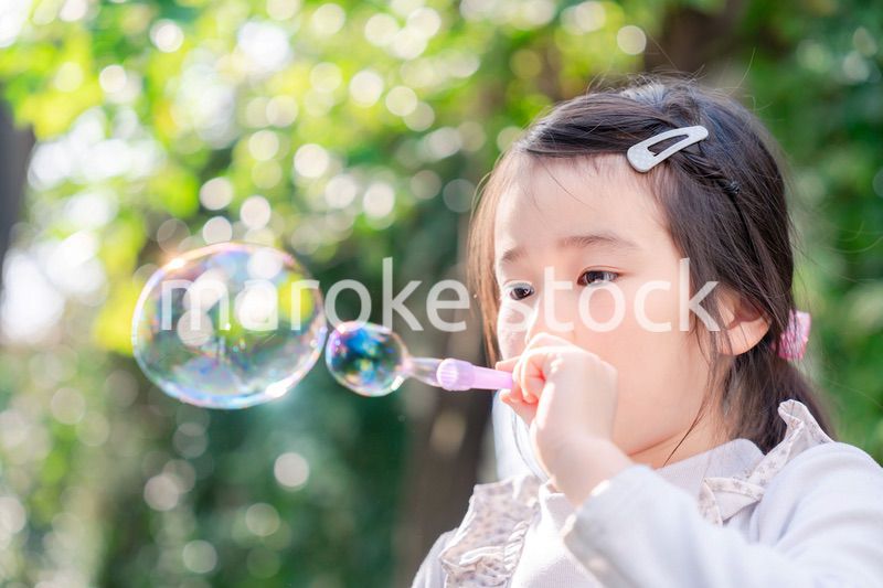シャボン玉をして遊ぶ小さな女の子