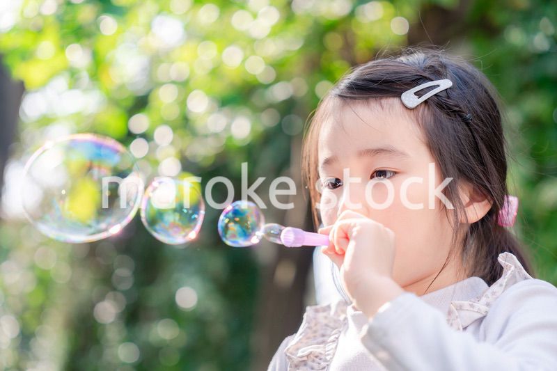 シャボン玉をして遊ぶ小さな女の子