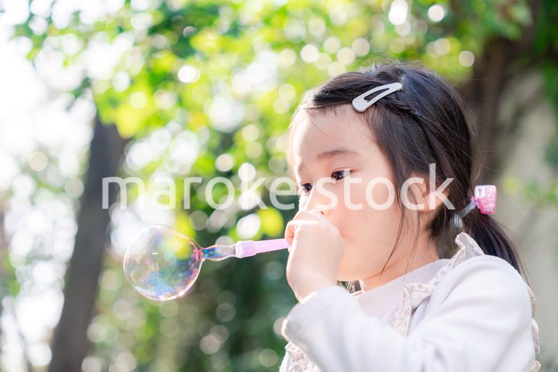 シャボン玉をして遊ぶ小さな女の子