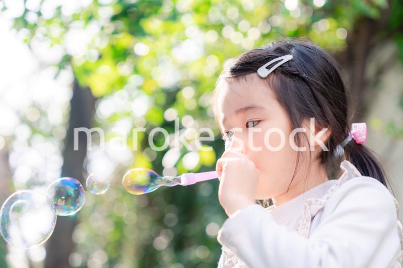 シャボン玉をして遊ぶ小さな女の子