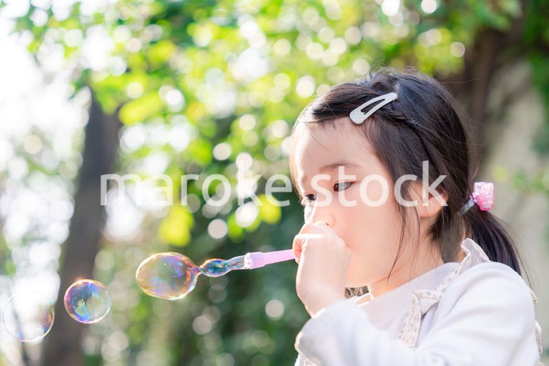 シャボン玉をして遊ぶ小さな女の子