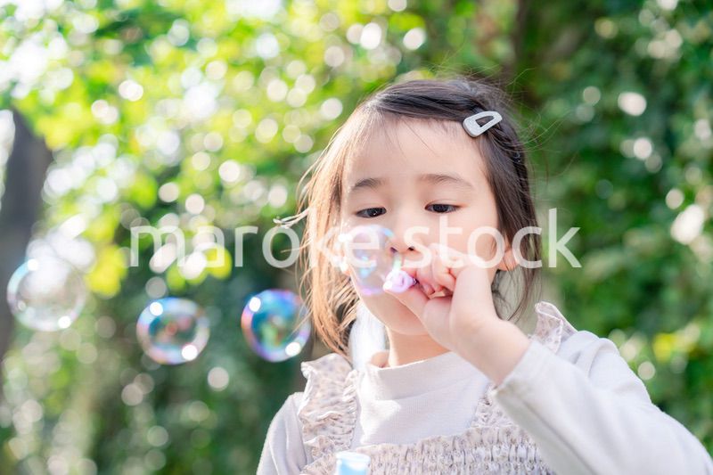 シャボン玉をして遊ぶ小さな女の子