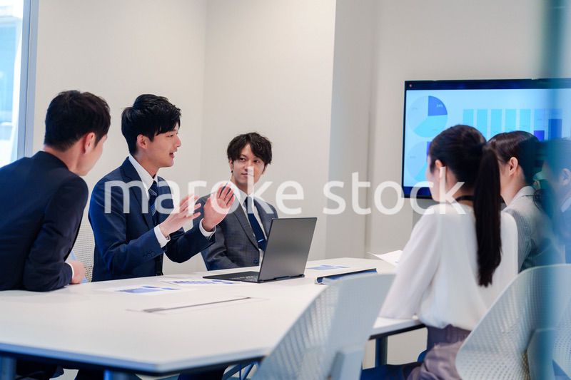 スーツを着て会議で話す若い男性