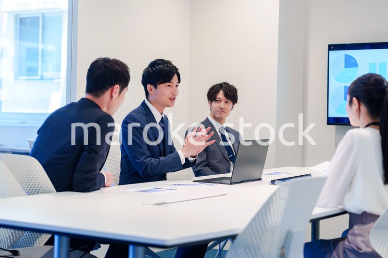 スーツを着て会議で話す若い男性