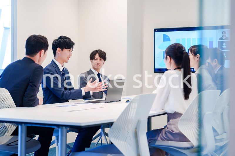 スーツを着て会議で話す若い男性