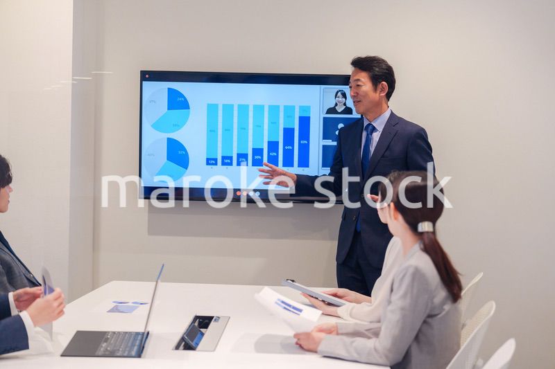 会議で資料を見ながらプレゼンをする中年のオフィスワーカー