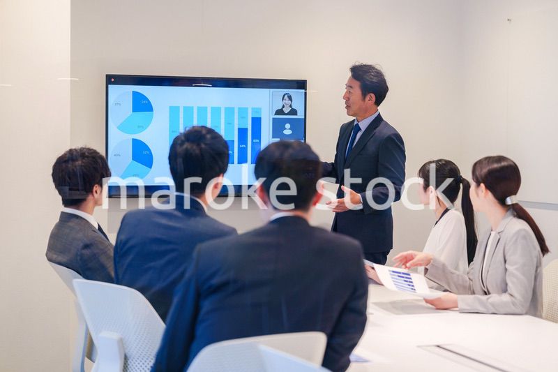 会議で資料を見ながらプレゼンをする中年のオフィスワーカー