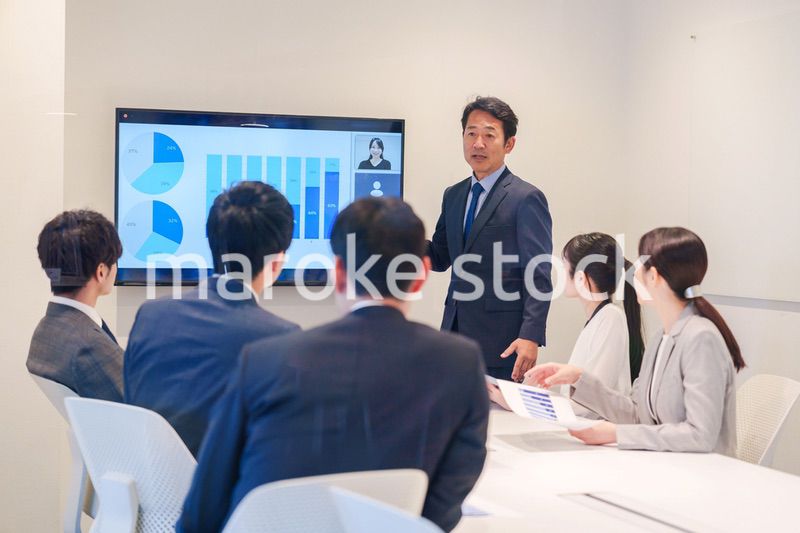 会議で資料を見ながらプレゼンをする中年のオフィスワーカー