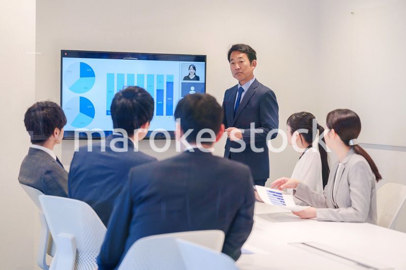 会議で資料を見ながらプレゼンをする中年のオフィスワーカー