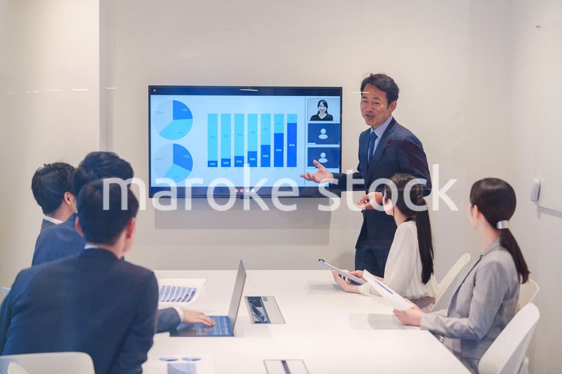 会議で資料を見ながらプレゼンをする中年のオフィスワーカー