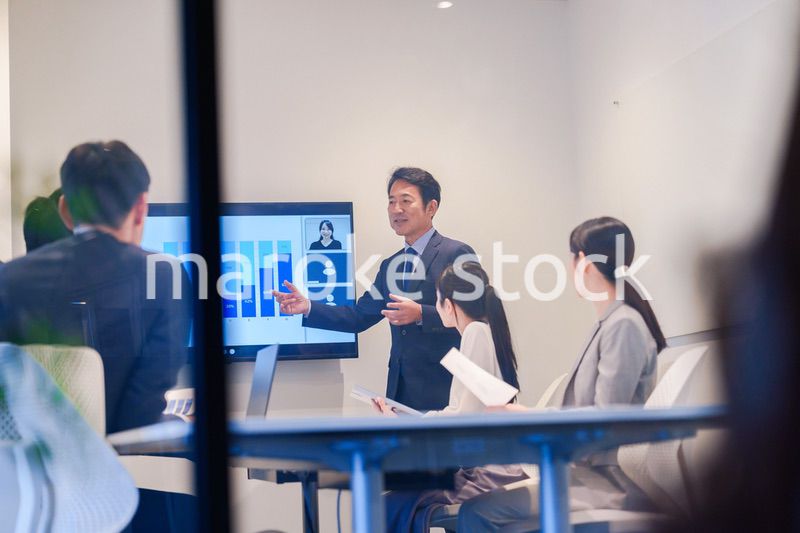 会議で資料を見ながらプレゼンをする中年のオフィスワーカー