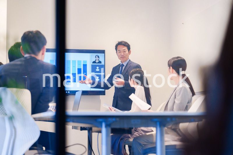 会議で資料を見ながらプレゼンをする中年のオフィスワーカー