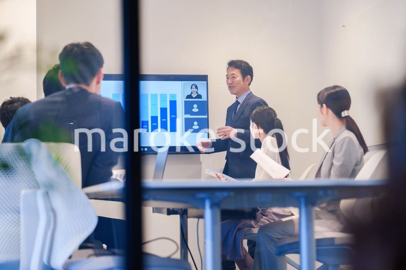 会議で資料を見ながらプレゼンをする中年のオフィスワーカー