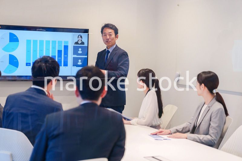 会議で資料を見ながらプレゼンをする中年のオフィスワーカー
