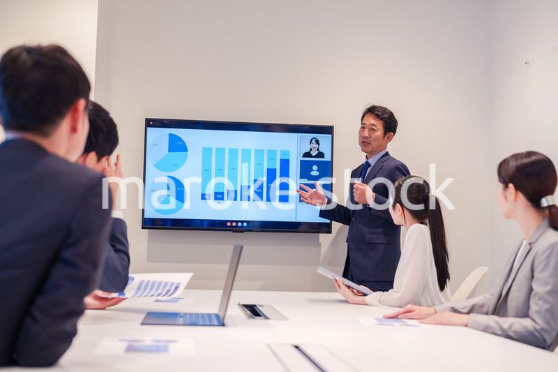 会議で資料を見ながらプレゼンをする中年のオフィスワーカー