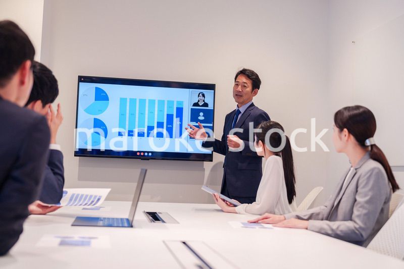 会議で資料を見ながらプレゼンをする中年のオフィスワーカー