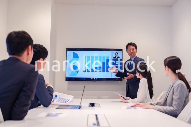 会議で資料を見ながらプレゼンをする中年のオフィスワーカー