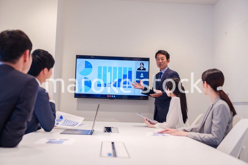 会議で資料を見ながらプレゼンをする中年のオフィスワーカー
