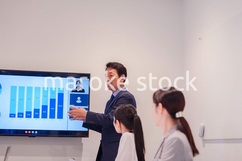会議で資料を見ながらプレゼンをする中年のオフィスワーカー