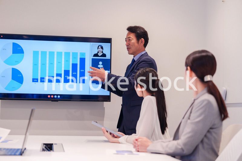 会議で資料を見ながらプレゼンをする中年のオフィスワーカー