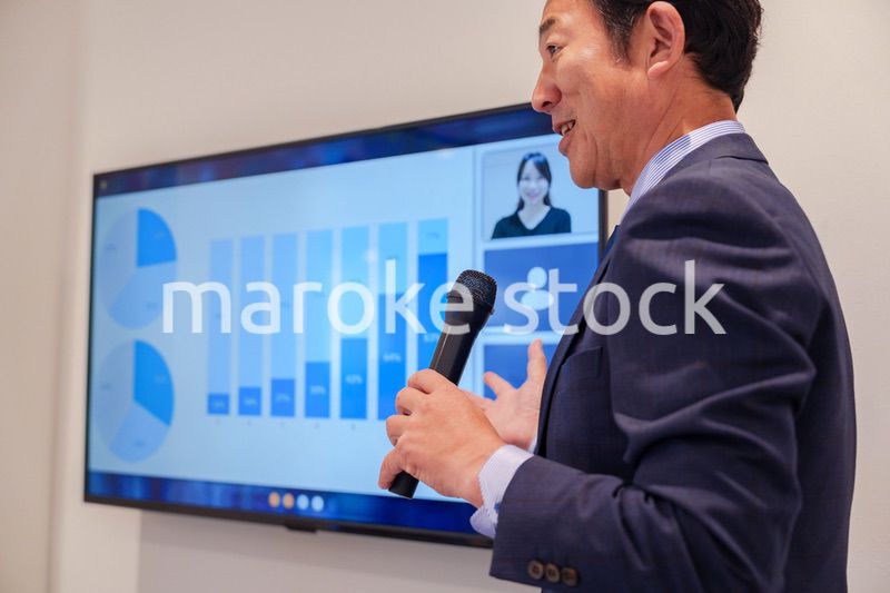 会議で資料を見ながらプレゼンをする中年のオフィスワーカー