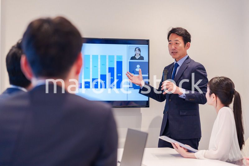 会議で資料を見ながらプレゼンをする中年のオフィスワーカー