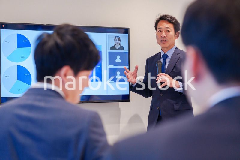 会議で資料を見ながらプレゼンをする中年のオフィスワーカー